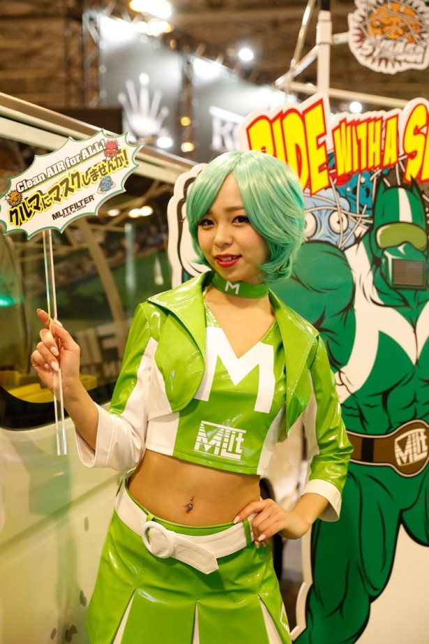 「オカダエンタープライズ」エリア(2号館/211)で、エアコンフィルター「MLITFILTER」を宣伝するキュートなコンパニオン