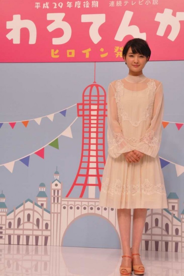 記念撮影に応える葵わかな。背景のイラストは通天閣。大阪の笑いをテーマにドラマが展開する
