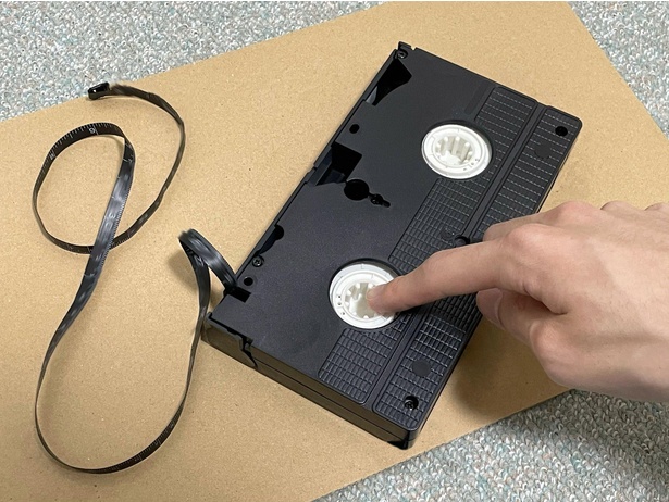 ビデオテープのはみ出しを再現したメジャー。リールハブ部分を押すと戻る仕組み