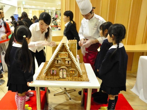 オープニングイベントで、パティシエのお兄さんやお姉さんに教えてもらいながら、お菓子の家のデコレーションを楽しむ地元の園児たち