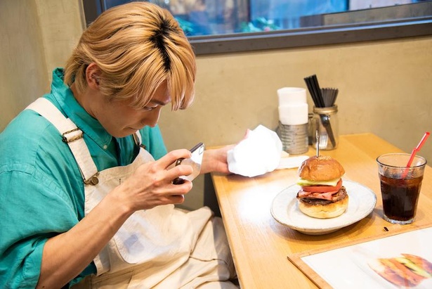 自分のスマホでハンバーガーを撮影する小林亮太