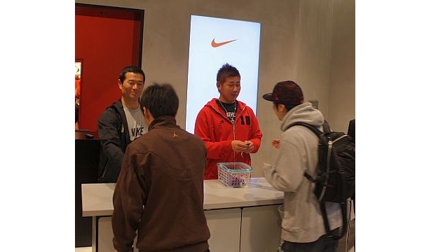 お守りを客に配る2人