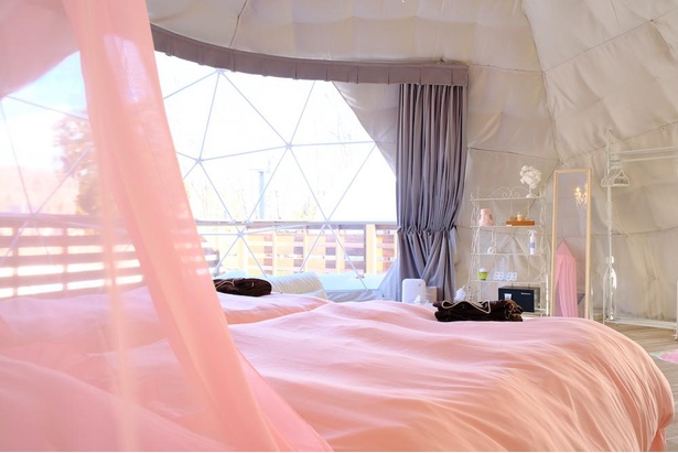 透きとおるピンクの布が吊るされた天蓋付きベッド