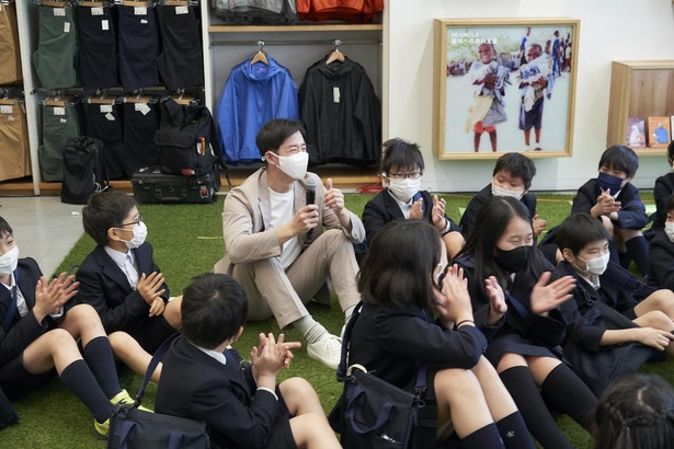 【写真】芝生スペースに子供たちと一緒に座り、授業の質問に答える斎藤佑樹さん