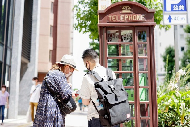 代々木公園への道中、渋谷公園通りのレトロな電話ボックスを発見。休憩しながら、別ルートの編集部員・Mの歩数を確認する有賀編集長とライター・H
