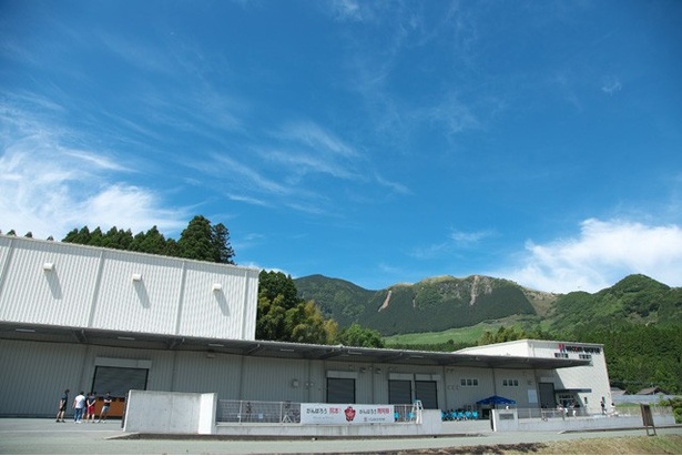 プレミアムウォーターの阿蘇採水地にある工場（ハイコムウォーター株式会社）。熊本県阿蘇郡南阿蘇村で平成26年1月より稼働を開始。後ろには阿蘇外輪山が見える