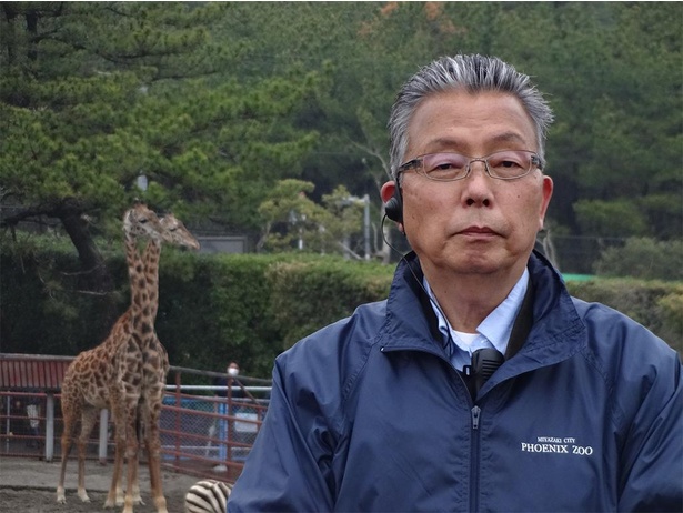 キリンの前に立つ竹田正人園長。「朝の巡回時に、キリンがふっとこちらを向いてくれる時、園長としてはうれしい」と話す