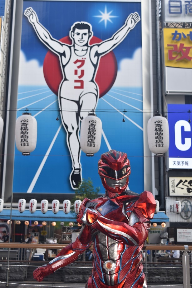 【写真を見る】道頓堀のシンボル・グリコの看板を背にポーズ