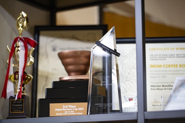 JBrC 2022 3位入賞の表彰カップや、COFFEE COLLECTION 2023 ウォッシュド部門1位のクリスタルトロフィーなど、園田さんがこれまでに獲得したトロフィーが並ぶ一角