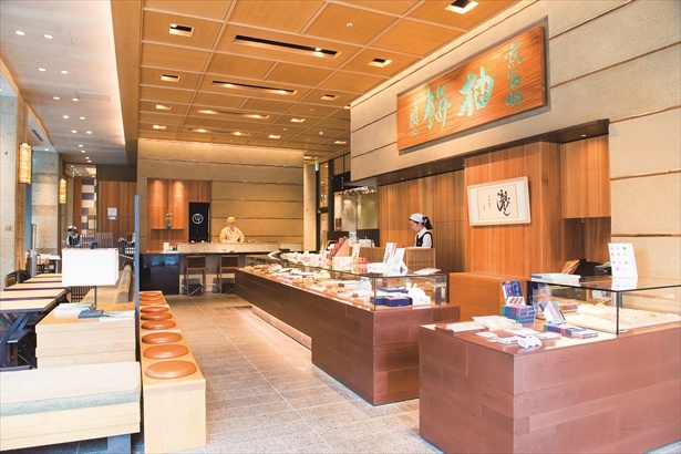店内には富岡鉄斎の揮毫による「柚餅」の看板が。内装は京都を思わせる素材で造られており、天井やランプには和紙、壁には陶器で直線が描かれ、数寄屋建築風に表現されている