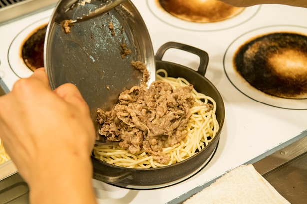 熱々の鉄鍋にパスタを敷き、牛肉をのせる