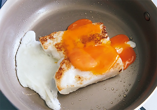 両面に焼き色が付いたら上から卵を割り、卵黄をつぶして表面に広げる