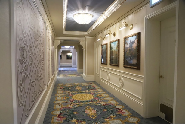 グランドシャトーの客室廊下。足元の絨毯には草花などが描かれ、壁にはディズニー映画をモチーフとした絵画が飾られている