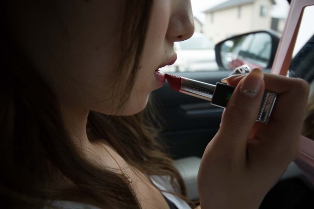 クルマの中で化粧直しをする彼女
