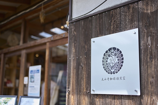 ロゴマークは、太山寺の紋である下り藤の中央にコーヒーの花を組み合わせたデザイン
