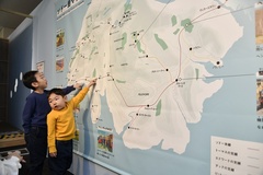 巨大なソドー島のマップの前でお気に入りの場所を探す2人
