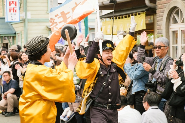 「ブギウギ祭」の開演を伝えるフラッグを持ち駆け巡る、新人巡査セイギ