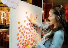 メッセージを書いたラブリーなシールを店頭のボードに貼るゆうちゃみさん