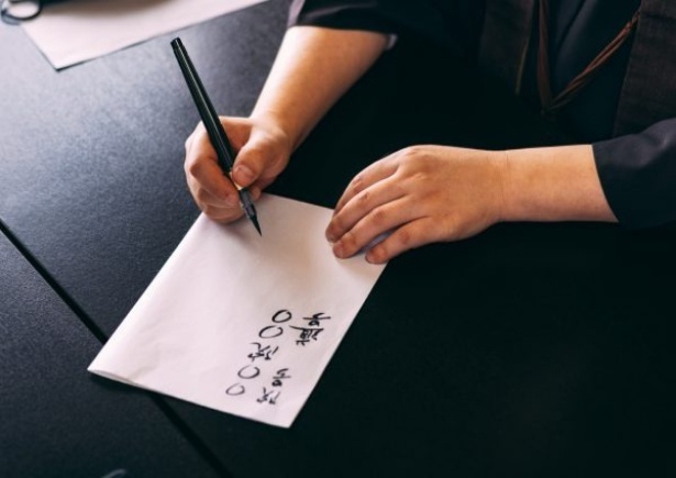 戒名を書きながら解説してくれる蝉丸P