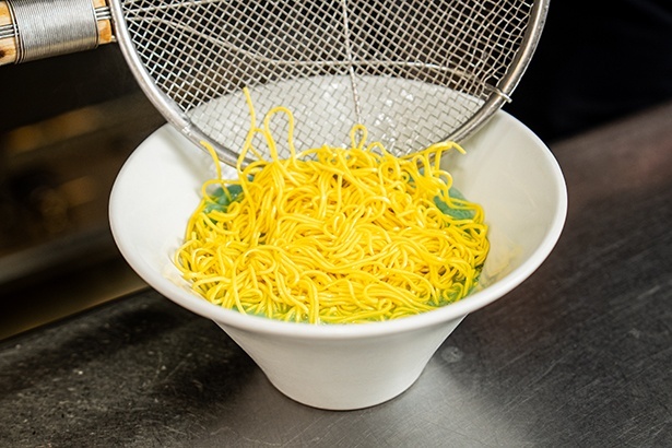 ブルーグリーンのスープにクチナシで着色した濃い黄色の麺が映える