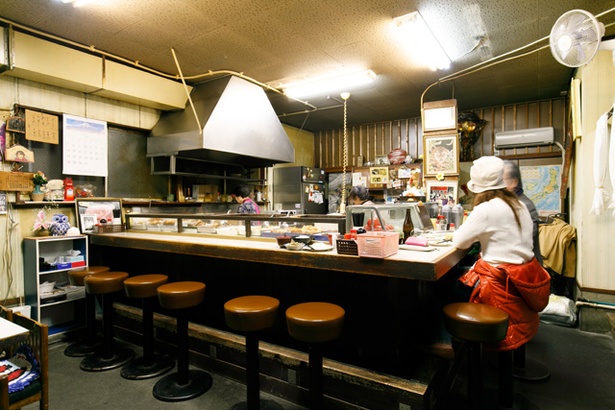 店内は総菜が並ぶL字カウンターとテーブル席がある