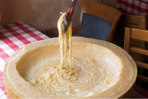 【写真を見る】「チーズカフェ」の｢24ヵ月熟成パルミジャーノ・レッジャーノ焦がしパスタ｣(1,814円)。大きなチーズの中でパスタを仕上げていくパフォーマンスも