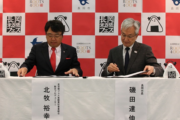 協定書にサインする総合プロデューサーの北牧裕幸氏(左)と長岡市長の磯田達伸氏(右)