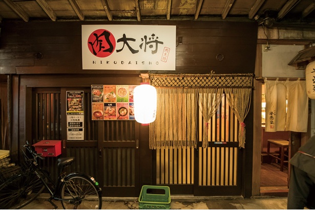 「肉大将」。大通り沿いの正面入口と2Fの座敷席に直結する裏口の2か所のエントランスがある