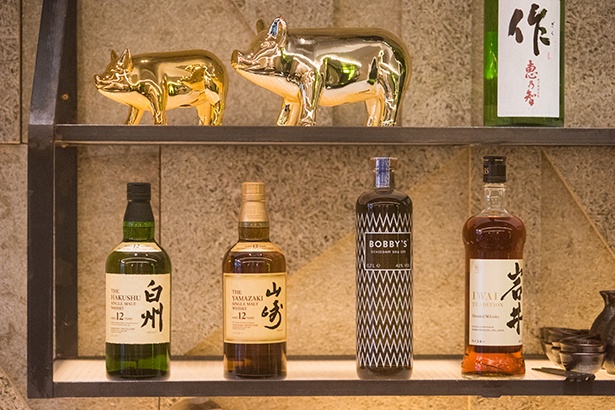 【写真を見る】バーカウンターの奥の棚には酒瓶がズラリ。「白州」や「山崎」などウイスキーは日本のものを各種取りそろえている