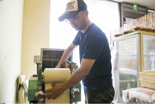 店主の李大偉さん。店内の一角にある製麺機で極太麺を作る。「防腐剤は使いません」