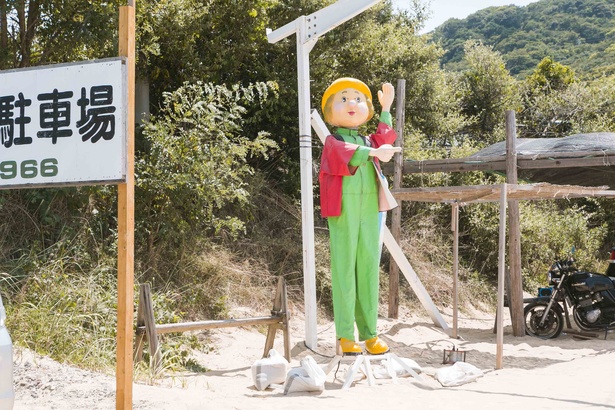 駐車場の入口に立つ「朝日屋」のキャラクター。シュールだ！
