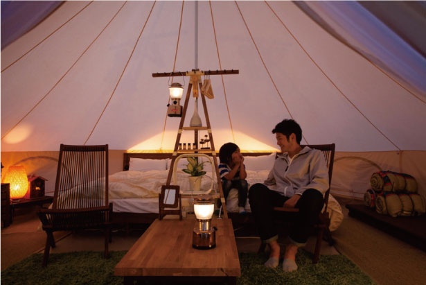 【写真】ザ ファームキャンプのグランピング施設。室内にはベッドやローテーブルまで！外のライティングも美しい