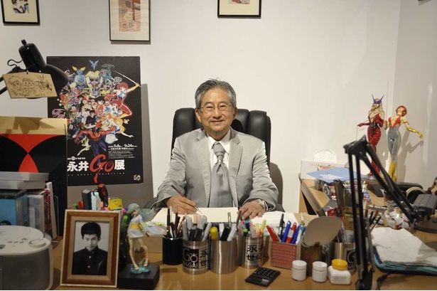 仕事場を再現した展示で、記念撮影に応える永井豪。手前の詰襟の肖像写真は永井本人