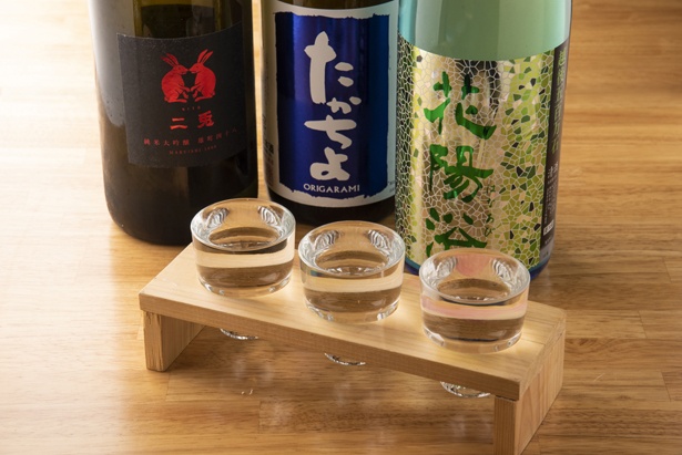 「名駅立呑 ばっかす おお島」の「大将おすすめ日本酒3種類飲み比べ」(1080円)。日本酒は常時30種類以上、季節限定や数量限定のレアなお酒もそろう。平日の17時以降限定だ