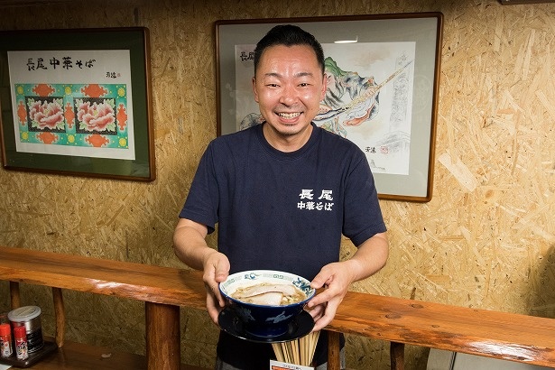 看板メニューの「こく煮干し」(850円)を差し出す店主の長尾大さん。「青森独特の煮干しラーメンをお楽しみください」