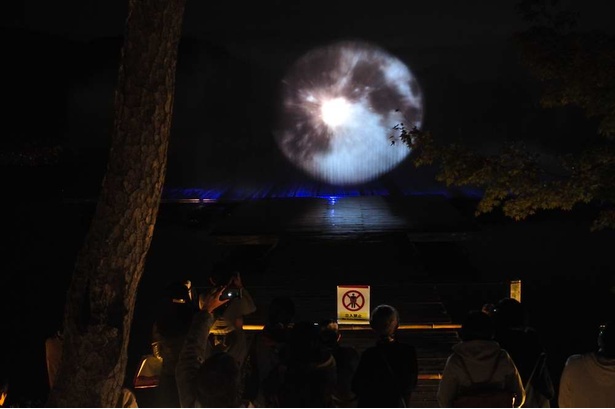 月の名所・大沢池に設けられたウォータースクリーンに、大きな月が昇り観客から歓声が上がる