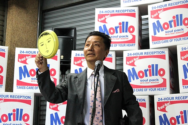 「M@福袋(3,000円)」の中身を、自ら解説する森村氏。直筆の顔が描かれた皿などレアなアイテムも！