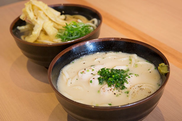 手前は水炊き風の鶏白湯あつかけうどん(1058円)、奥は博多の定番・ごぼう天あつかけうどん(864円)