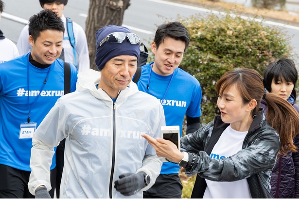 走るランナーに声をかける湯田さん（右）
