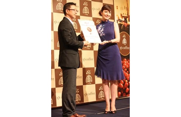 成都邱公館食品株式会社の金社長から、「PR大使認定証」を受け取るモナさん