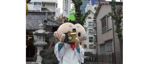 報道陣にカメラを向けるお茶目な「おしなりくん」