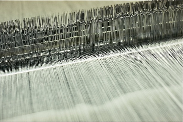 1本1本の経糸を織機に通す作業はかつて人の手で行われていた。すべての糸を通すのには半日以上かかったという。