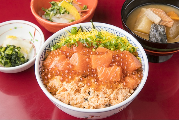 「北海道料理ユック 横浜西口店」のランチの鮭親子丼980円。脂ののった北海道直送サケの漬け、サケフレーク、イクラがご飯をおおうオリジナル。石狩汁、小鉢、漬物付き