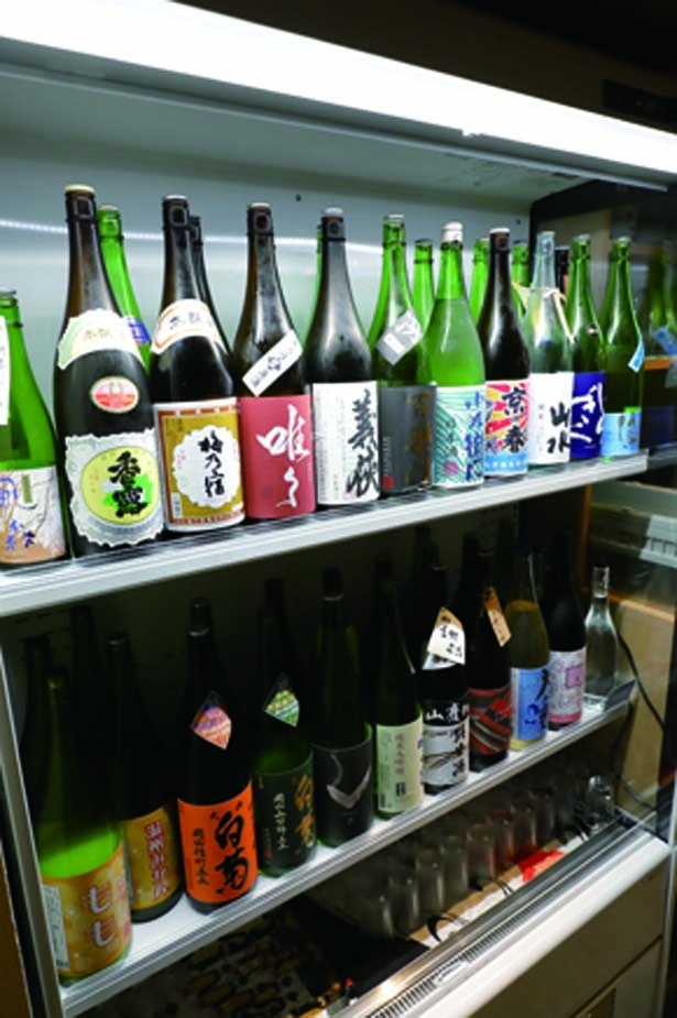 【写真を見る】ショーケースから自由にお酒を選べる。ケースごとに西日本と東日本の銘柄に分けられている/日本酒×発酵 八光(はちみつ)