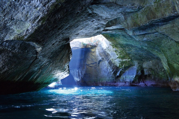 【写真を見る】洞窟の上から光が射し込み、海面を照らす / 堂ヶ島天窓洞