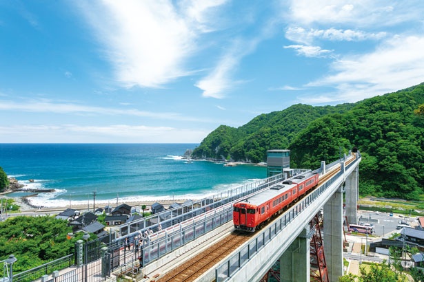 【写真を見る】JR山陰本線の列車と日本海、新緑の山々をめでられるのは空の駅ならでは/余部鉄橋 空の駅