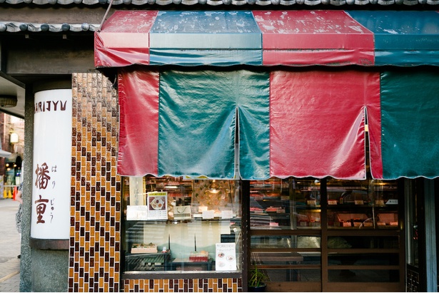 赤と緑の暖簾がかかる精肉店の店頭では、ミンチカツやビフカツサンドも販売している