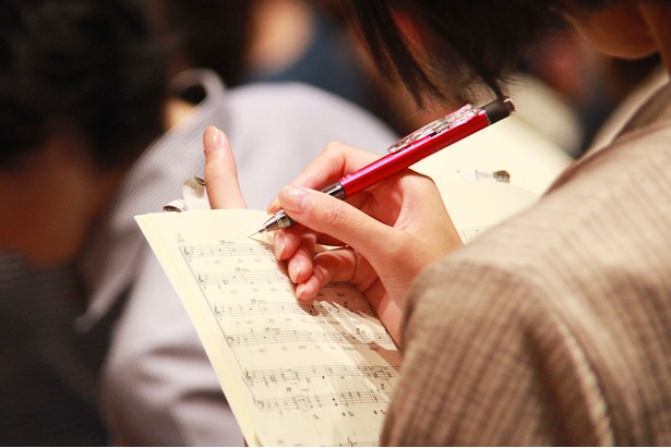鉛筆や色とりどりのペンで楽譜にポイントを書き込む参加者/サントリー1万人の第九