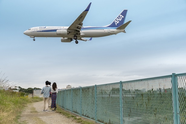 目の前を通過する飛行機。頭上約20メートルを通過するとあって、ジェットエンジンの噴射による風は、土手の砂を巻き上げるほど