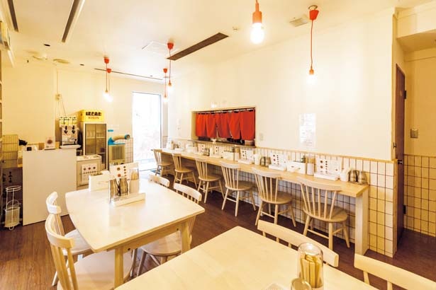 カウンターとテーブルが並ぶ店内は、白と赤を基調とした明るい雰囲気/辛麺屋 一輪 大阪店